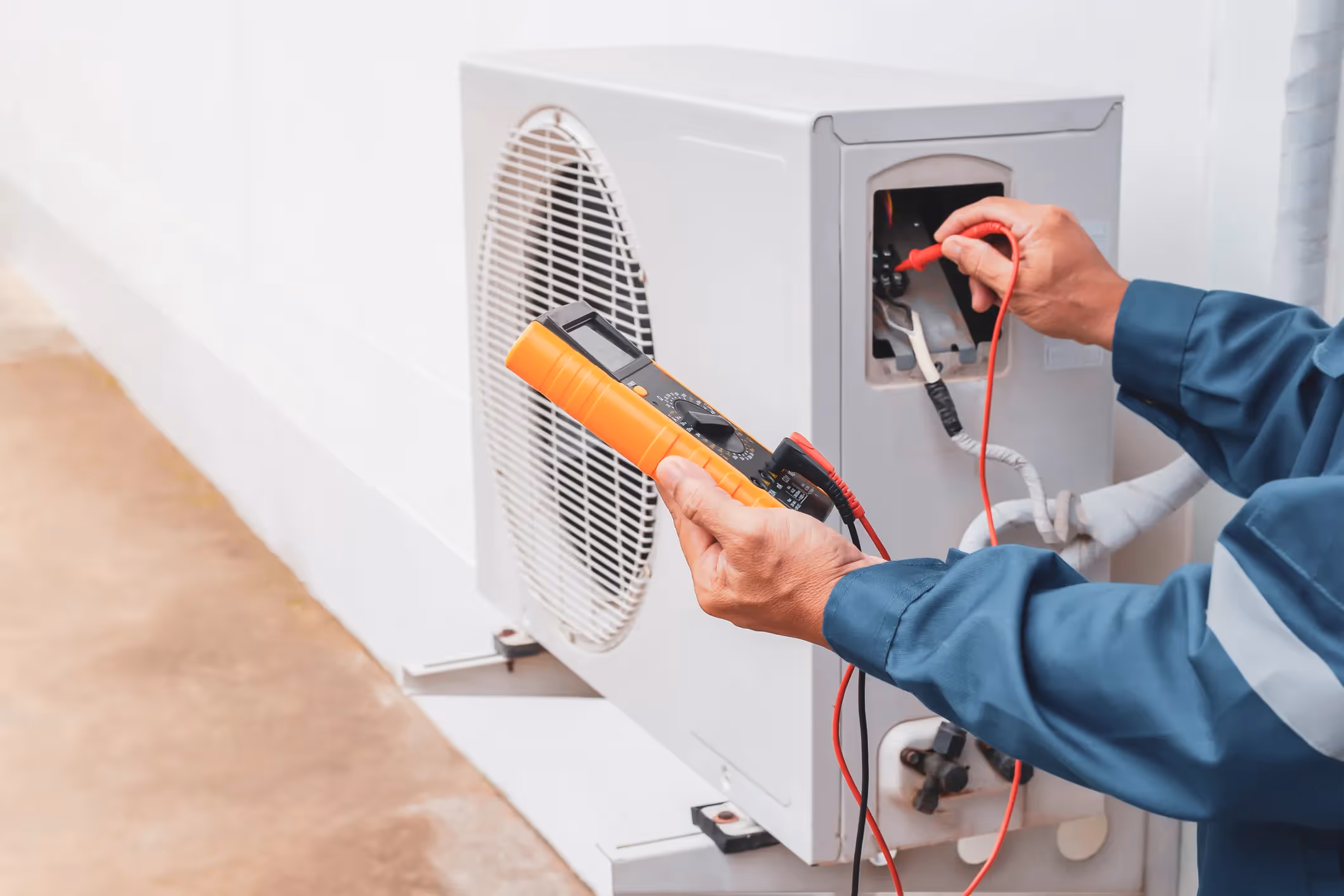 Professional HVAC technician using digital gauges to test the electrical connections and voltage of an indoor air handler