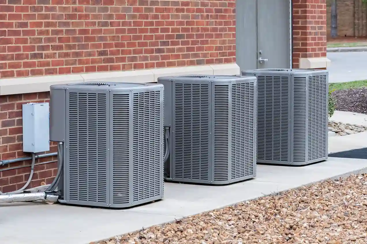 clean modern outdoor AC condenser unit on gravel pad next to brick home