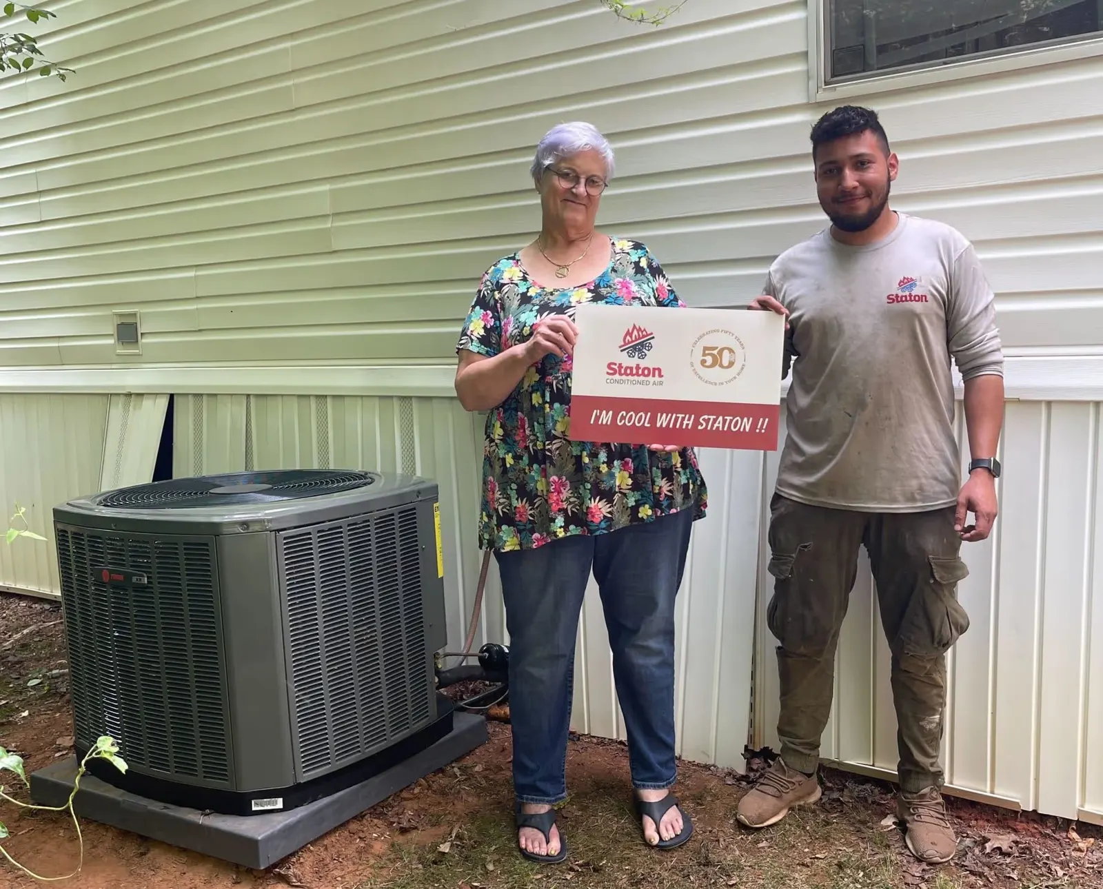 Happy homeowners beside their new outdoor AC unit