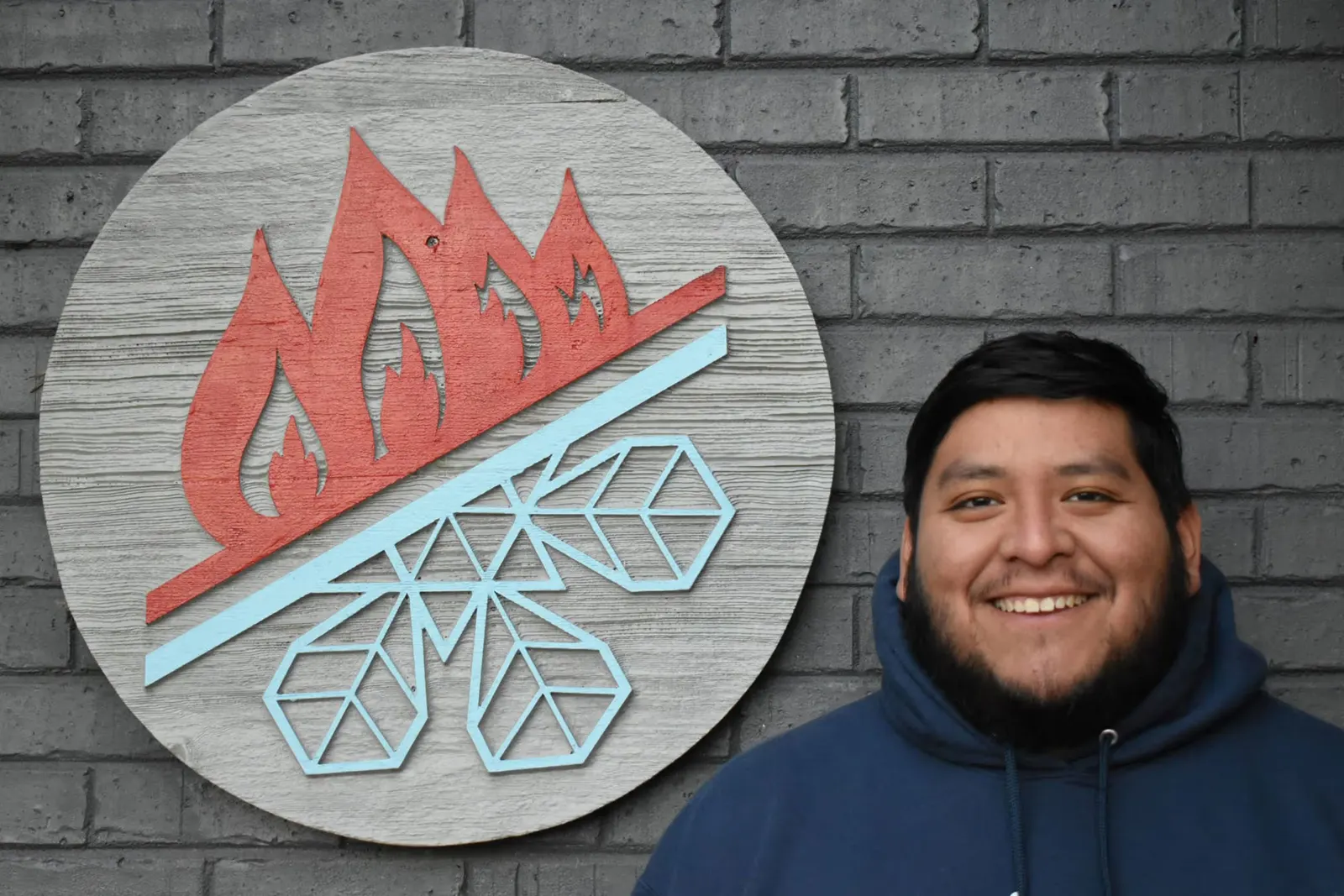 Staton team member in front of the flame-and-snowflake logo wall